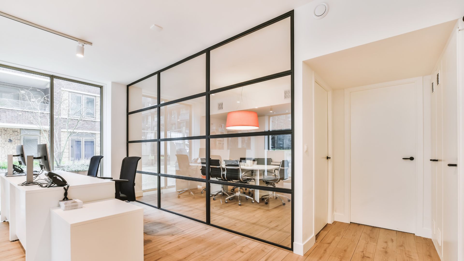 A room with a desk, chairs, and a large window