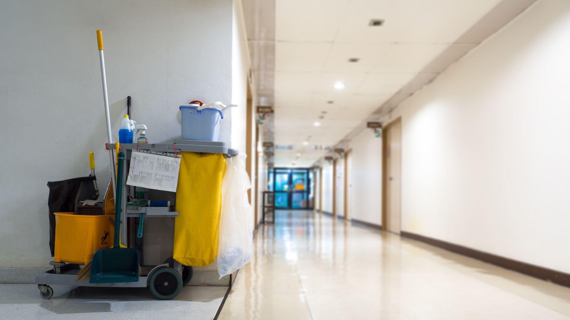 A hallway with a mop, buckets and cleaning supplies