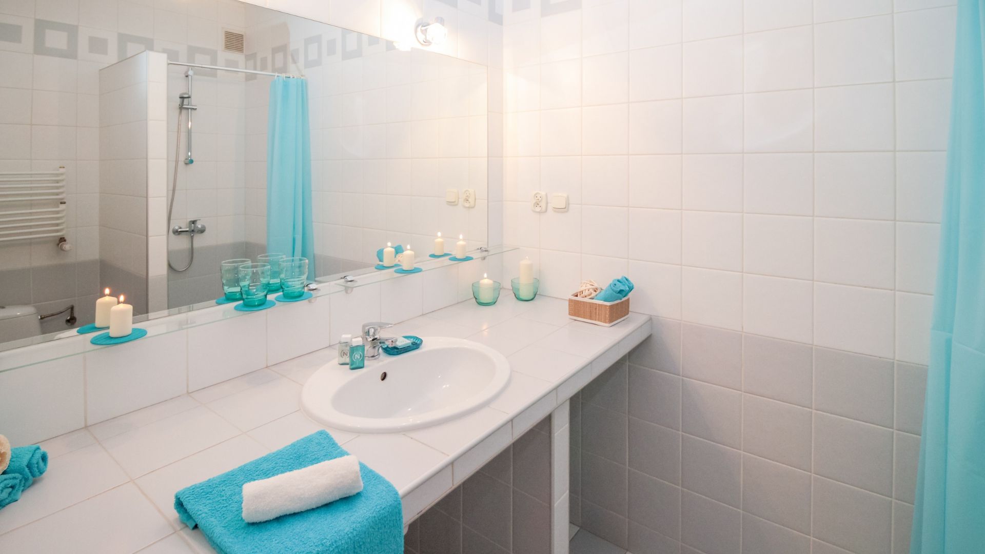 A bathroom with a sink, mirror and blue towels