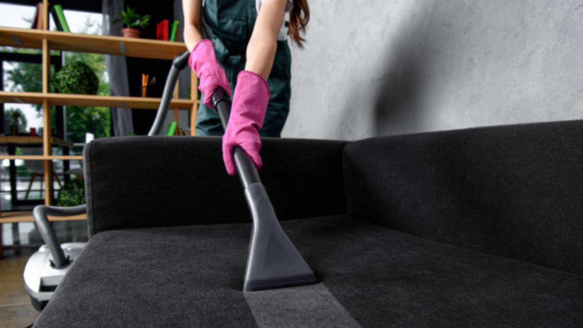 A woman cleaning a couch with a vacuum